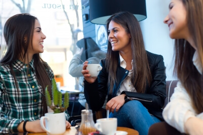 three young women drinking coffee at cafe shop